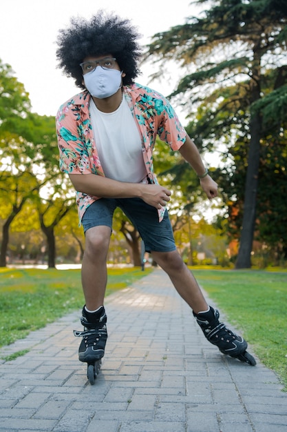Portrait de jeune homme portant un masque facial en patinage à roulettes en plein air dans la rue