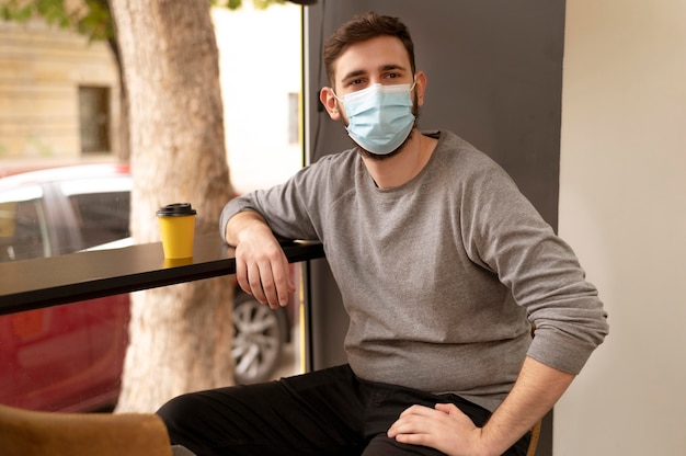 Photo portrait de jeune homme portant un masque médical dans un café