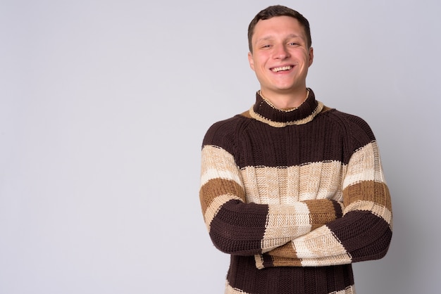 Portrait de jeune homme portant un pull à col roulé prêt pour l'hiver contre le mur blanc