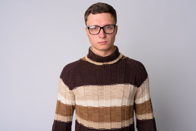 Portrait de jeune homme portant un pull à col roulé prêt pour l'hiver contre le mur blanc