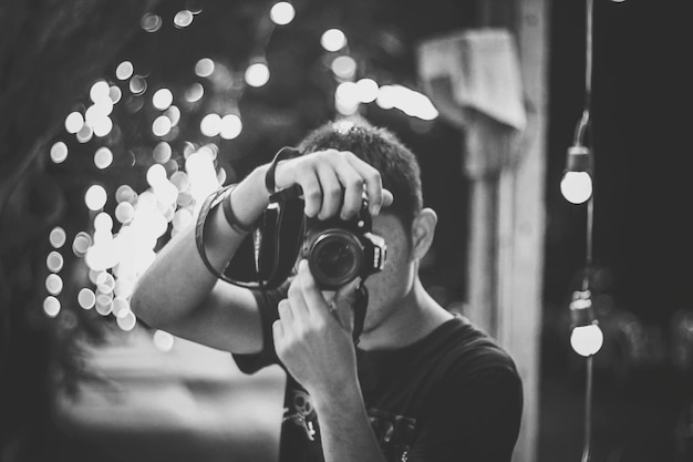 Portrait d'un jeune homme prenant des photos avec une caméra éclairée