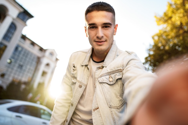 Portrait de jeune homme prenant un selfie tout en étant dans la rue de la ville en gros plan