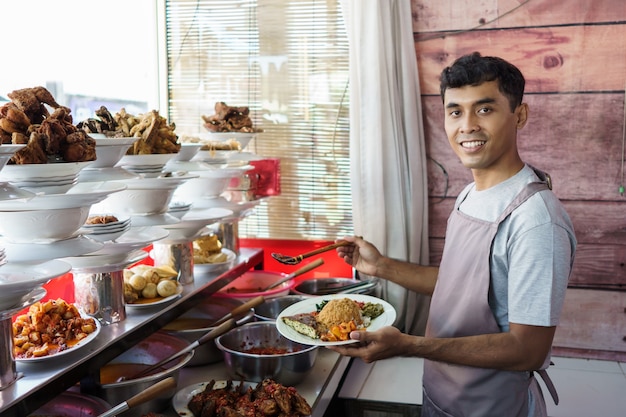 Portrait jeune homme qui prépare une cuisine traditionnelle