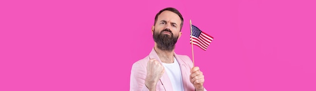 Portrait d'un jeune homme satisfait avec une barbe avec un drapeau américain sur un fond de studio rouge Grand patriote américain et défenseur de la liberté