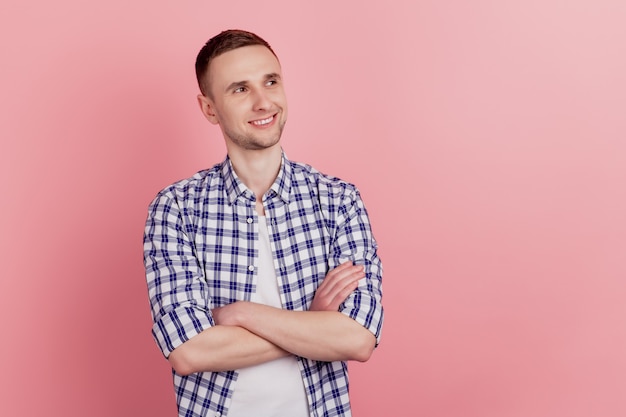 Portrait d'un jeune homme séduisant, les mains croisées, regard de rêve, espace vide, confiant, isolé sur fond de couleur rose