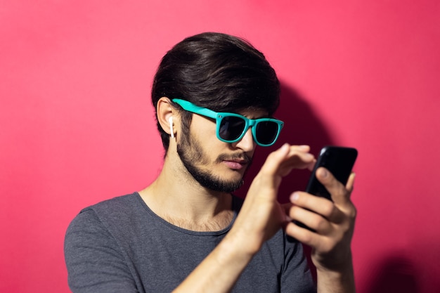 Portrait de jeune homme avec smartphone en mains écouter de la musique sur des écouteurs sans fil