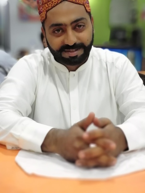 Photo portrait d'un jeune homme souriant assis à table