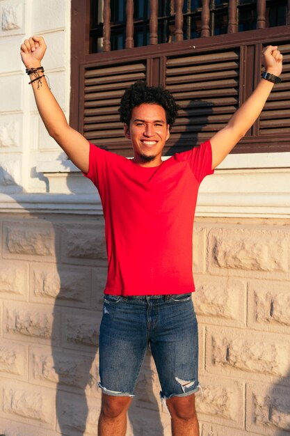 Portrait d'un jeune homme souriant, les bras en l'air.