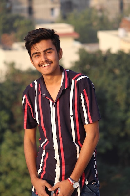 Portrait d'un jeune homme souriant debout à l'extérieur