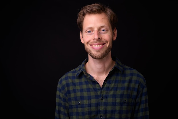 Photo portrait d'un jeune homme souriant sur un fond noir