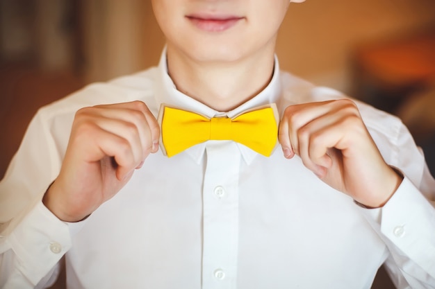 Photo portrait de jeune homme souriant heureux dans un costume de mariage et cravate papillon jaune. fermer. mains, lèvres.