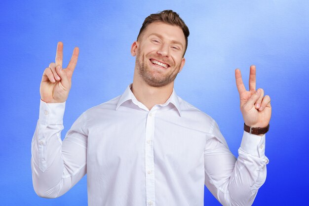 Portrait d&#39;un jeune homme souriant avec signe de victoire