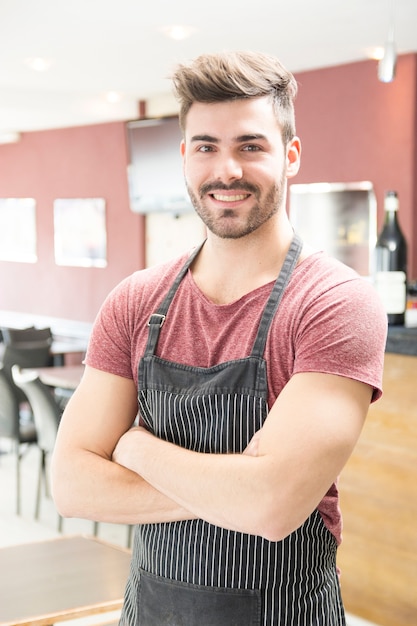 Portrait de jeune homme souriant avec tablier debout dans le bar