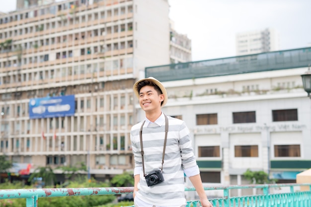 Portrait d'un jeune homme souriant voyageant avec une valise
