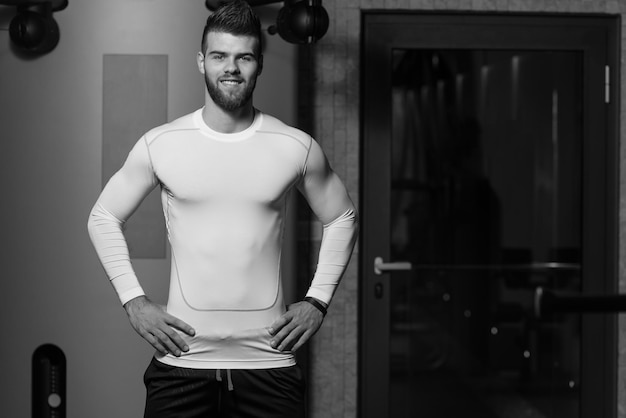 Portrait d'un jeune homme sportif dans la salle de sport moderne avec équipement d'exercice