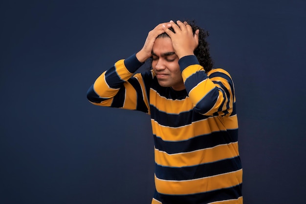 Portrait d'un jeune homme stressé ou souffrant d'un mal de tête sur fond gris