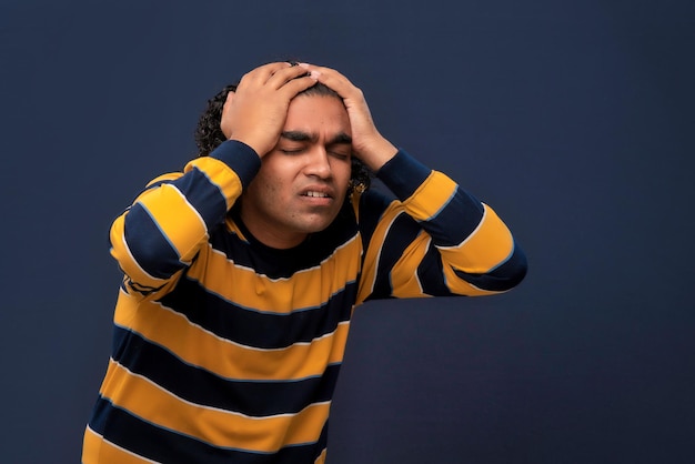 Portrait d'un jeune homme stressé ou souffrant d'un mal de tête sur fond gris