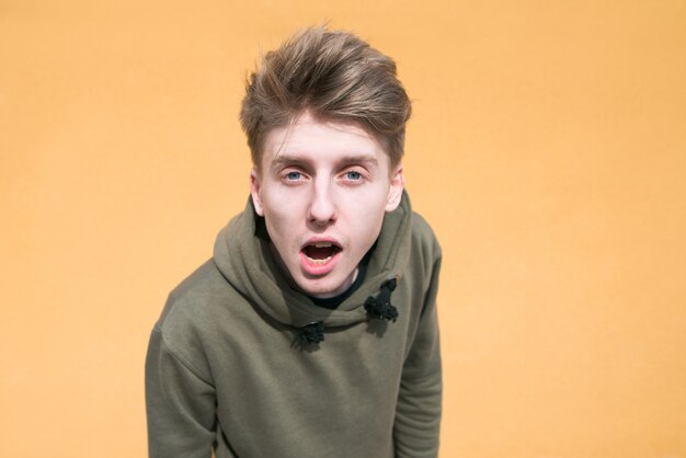 Photo portrait d'un jeune homme surpris sur un mur orange.