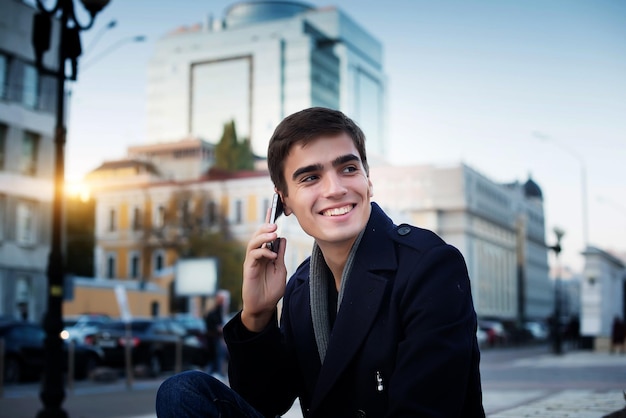 Portrait d'un jeune homme avec un téléphone dans les mains.