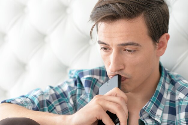 Portrait d'un jeune homme avec téléphone à la maison