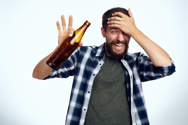 Photo portrait d'un jeune homme tenant une bouteille sur un fond blanc