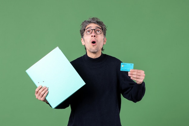 Portrait de jeune homme tenant un document et une carte de crédit sur fond vert nature banque argent enseignant emploi masculin