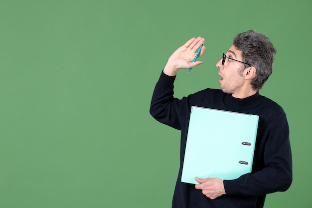 Portrait de jeune homme tenant des documents tourné en studio sur fond vert enseignant de cours d'emploi d'affaires