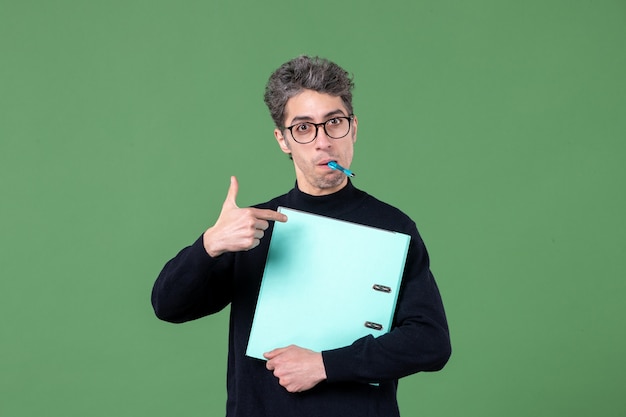 Portrait de jeune homme tenant des documents tourné en studio sur fond vert entreprise d'emploi d'enseignant