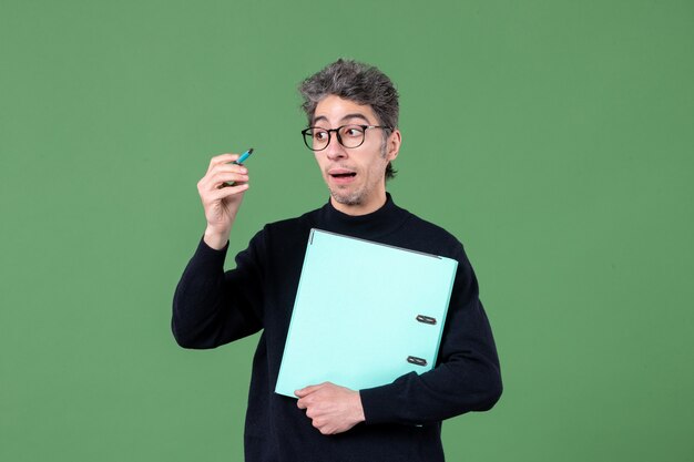 Portrait de jeune homme tenant des documents tourné en studio sur fond vert leçon de travail de professeur d'emploi