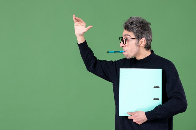 Portrait de jeune homme tenant des documents tourné en studio sur fond vert professeur de cours d'emploi