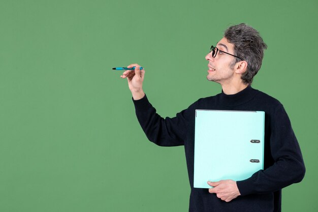 Portrait de jeune homme tenant des documents tourné en studio sur fond vert travail d'enseignant d'entreprise