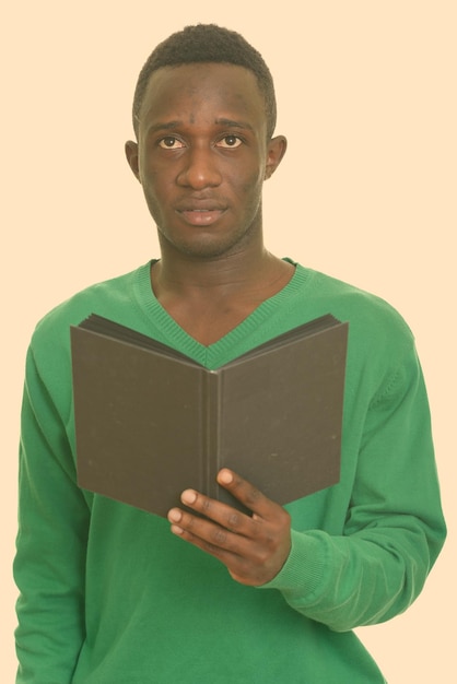 Photo portrait d'un jeune homme tenant un livre sur un fond blanc