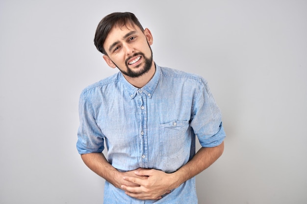 Portrait de jeune homme tenant les mains sur son ventre souffrant de douleur et d'inconfort intestinal isolé sur fond blanc