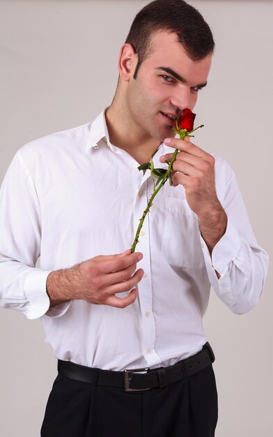 Photo portrait d'un jeune homme tenant une rose sur un fond blanc