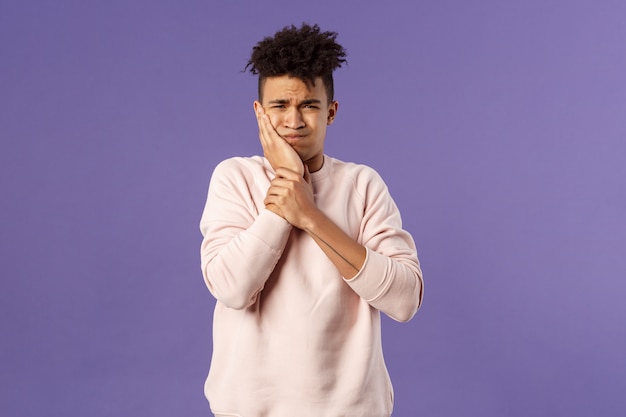 Portrait d'un jeune homme troublé, ressentant une douleur douloureuse dans les dents, des maux de dents ou une carie, touchant une joue avalée grimaçant mal à l'aise, besoin de voir un dentiste, faisant la queue pour un rendez-vous,