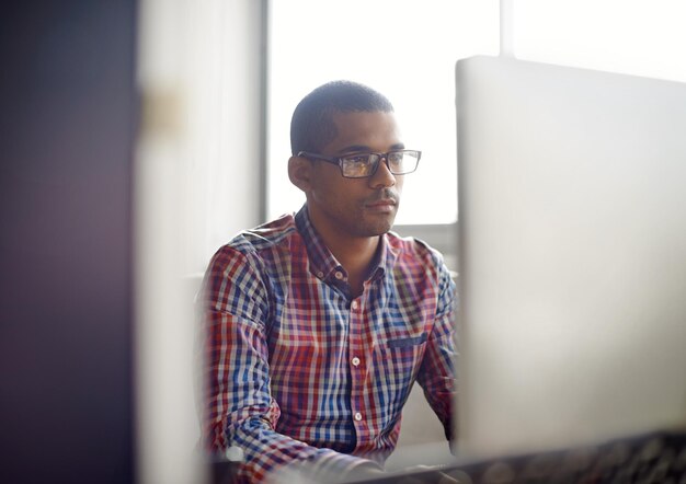 Photo portrait d'un jeune homme utilisant un téléphone portable alors qu'il se tient au bureau