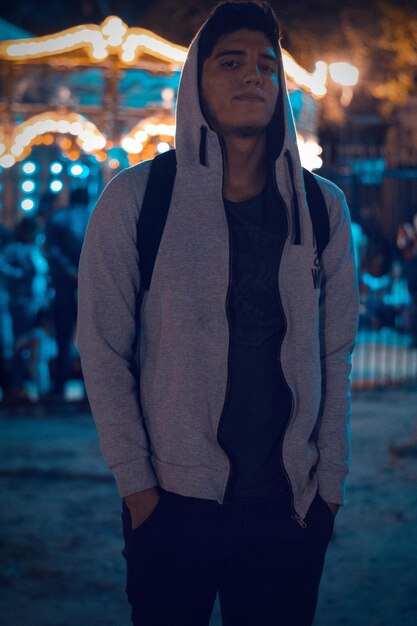 Photo portrait d'un jeune homme en veste à capuche debout dans la rue la nuit