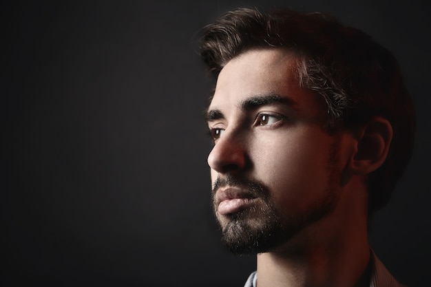 Portrait de jeune homme. Visage en gros plan. Fond noir