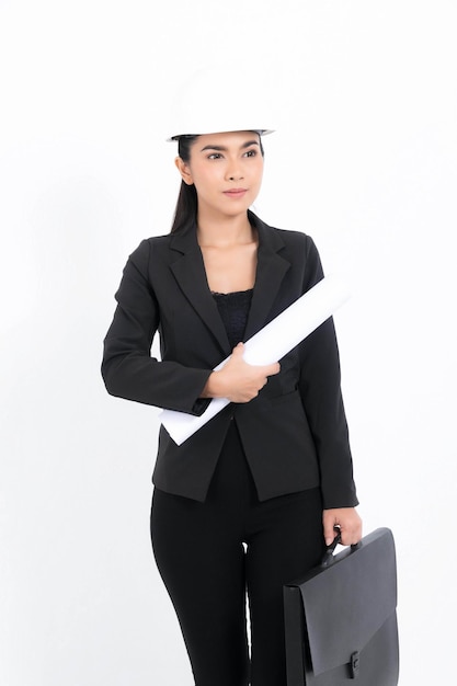 Portrait jeune ingénieur femme portant un costume noir et un casque de sécurité blanc tenant un plan et un sac en studio photo isolé sur fond blanc.