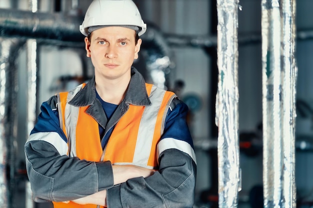 Portrait de jeune ingénieur de l'industrie lourde en gilet de protection et vêtements de travail et casque