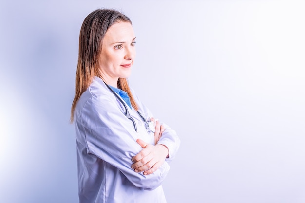 Portrait de jeune jolie docteur de profil pensif regardant parlé avec le concept de médecine de bras croisés