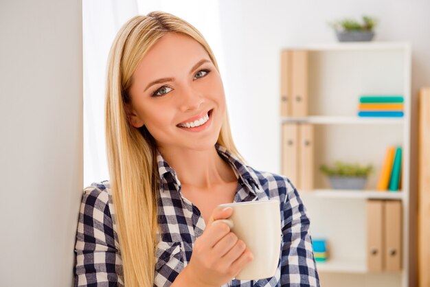 Portrait de jeune jolie femme ayant pause et tenant la tasse avec du thé