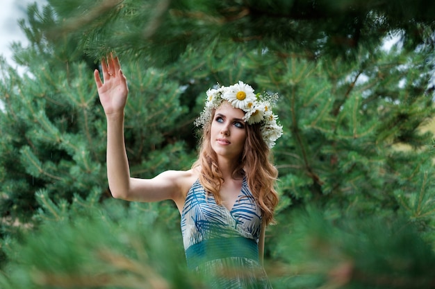 Portrait de jeune jolie femme avec un cercle de fleurs de camomille sur la tête