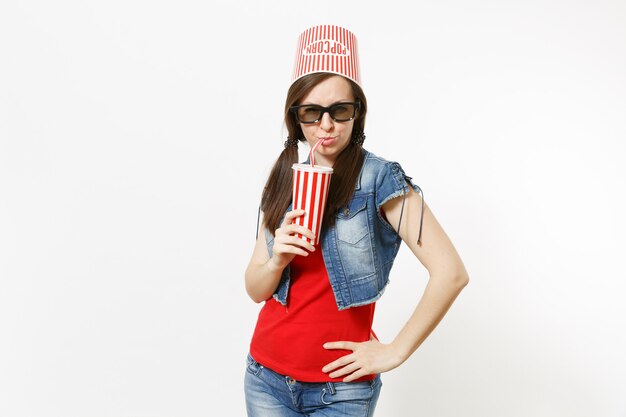 Portrait De Jeune Jolie Femme Drôle Dans Des Lunettes 3d Avec Seau Pour Pop-corn Sur La Tête En Regardant Un Film Et En Buvant Du Soda Ou Du Cola Dans Une Tasse En Plastique Isolée Sur Fond Blanc. Les émotions Au Cinéma.