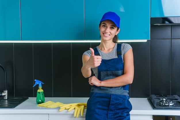 Portrait de jeune jolie femme de service de nettoyage professionnel montre le pouce vers le haut.