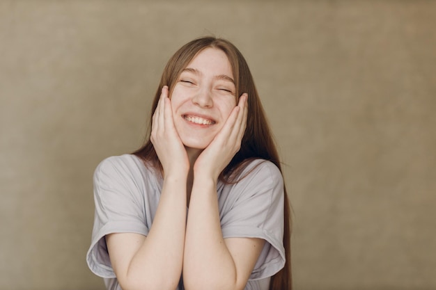 Portrait de jeune jolie femme souriante regardant la caméra sur fond beige