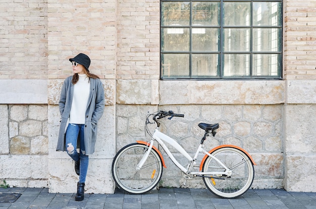 Un portrait jeune jolie fille de race blanche, appuyé contre le mur avec un vélo dans la ville