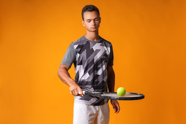 Portrait d'un jeune joueur de tennis sur fond orange