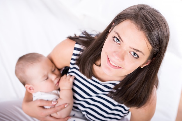 Portrait d&#39;une jeune maman heureuse tient un bébé qui dort.