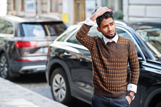 Portrait de jeune mannequin indien élégant pose dans la rue contre la voiture suv